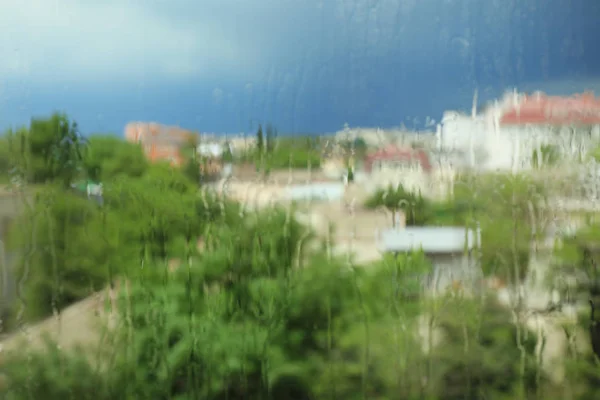 Vista borrosa de la ciudad desde la ventana en el día lluvioso — Foto de Stock