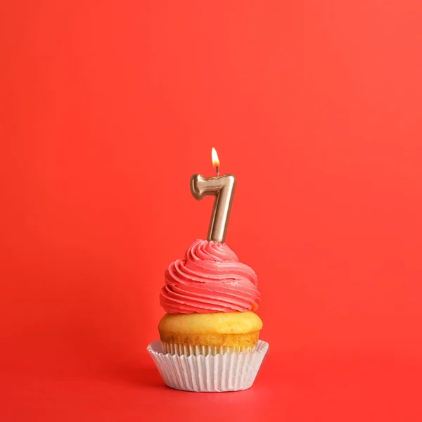 Cupcake d'anniversaire avec numéro sept bougie sur fond rouge — Photo