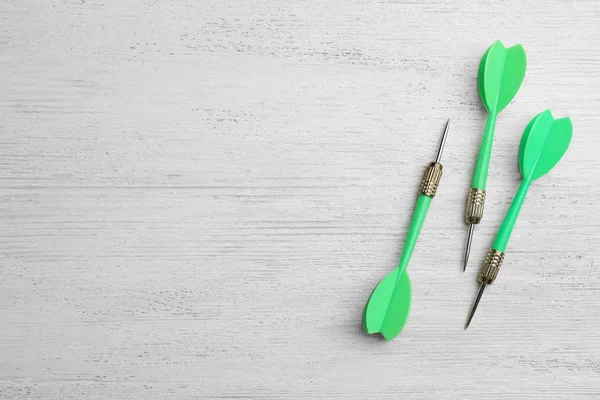 Flechas de dardo verde en la mesa de madera blanca, plano con espacio para el texto — Foto de Stock