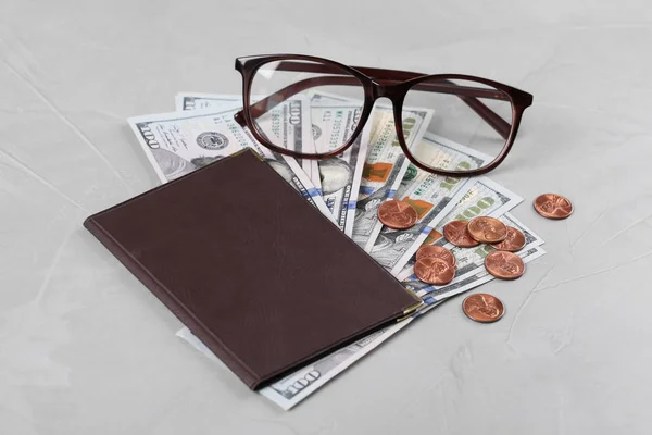 Пенсионный сертификат с американскими деньгами и очками на фоне серого камня — стоковое фото