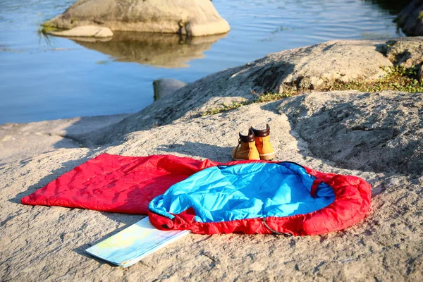 Bolsa de dormir, botas y mapa al aire libre en un día soleado — Foto de Stock