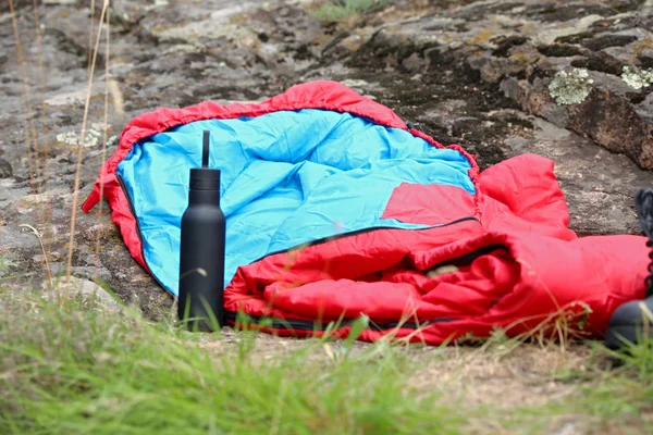Bolsa de dormir y botella al aire libre. Equipo de camping — Foto de Stock