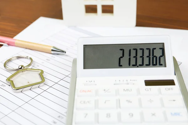 Calculadora, baratija en forma de casa, bolígrafo y documentos sobre la mesa. Lugar de trabajo del agente inmobiliario — Foto de Stock