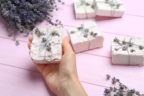 Mulher segurando mão fez sabão bar com flores de lavanda no fundo de madeira rosa, close-up — Fotografia de Stock