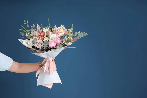 Man holding beautiful flower bouquet on blue background, closeup view. Space for text