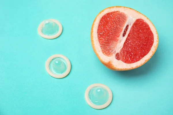 Die Hälfte Grapefruit und Kondome auf türkisfarbenem Hintergrund, oben Ansicht. Sexualkonzept — Stockfoto