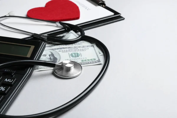 Stethoscope with money and calculator on white background. Health insurance concept