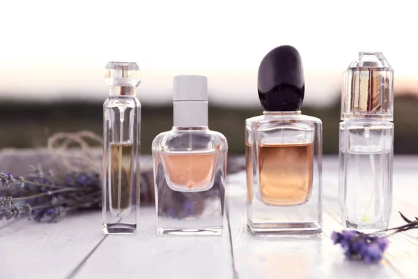 Bouteilles de parfum de luxe et fleurs de lavande sur table en bois blanc à l'extérieur — Photo