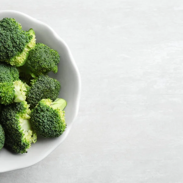 Ciotola di broccoli freschi su tavolo grigio chiaro, vista dall'alto con spazio per il testo — Foto Stock