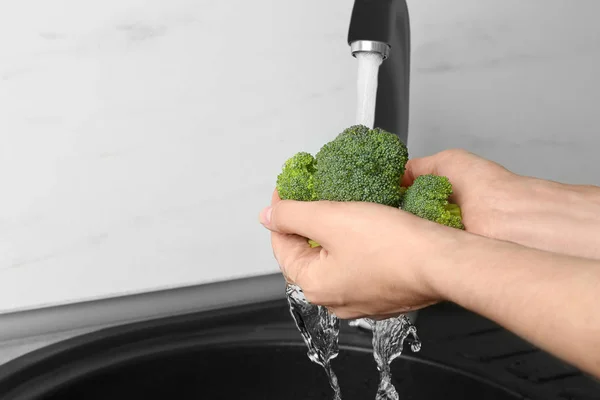 Woman washing fresh green broccoli in kitchen sink, closeup view. Space for text — Stock Photo, Image