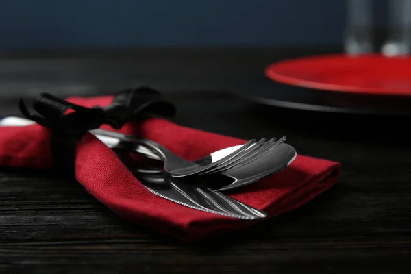 Cutlery set and dishware on black wooden table, closeup