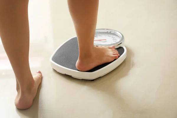 Woman stepping on floor scales indoors. Overweight problem — Stock Photo, Image