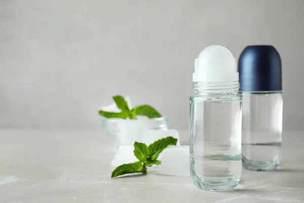 Roll-on deodorants and ice cubes with mint on light grey table, space for text — Φωτογραφία Αρχείου