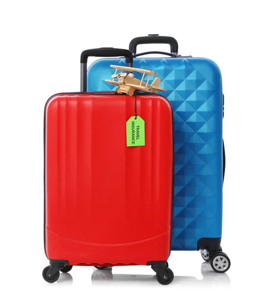 Rote und blaue Koffer mit Reiseversicherungsetikett auf weißem Hintergrund — Stockfoto