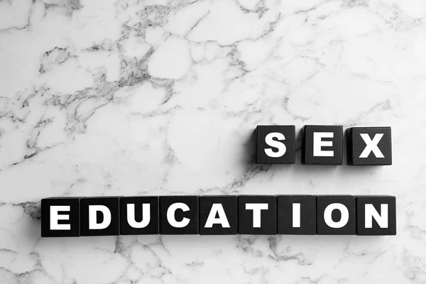 Black wooden blocks with phrase "SEX EDUCATION" on marble background, flat lay — Stock Photo, Image