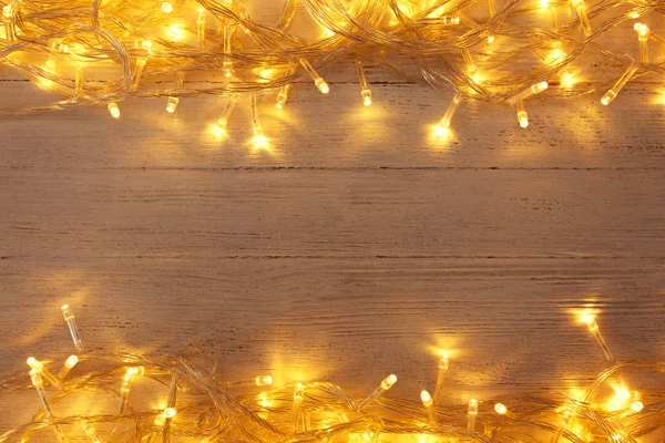 Leuchtende Weihnachtsbeleuchtung auf weißem Holzhintergrund, Draufsicht. Raum für Text — Stockfoto