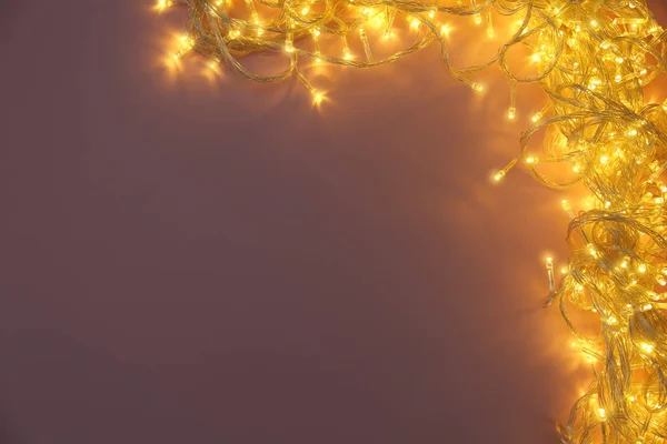 Leuchtende Weihnachtsbeleuchtung auf violettem Hintergrund, Draufsicht. Raum für Text — Stockfoto