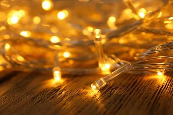 Leuchtende Weihnachtslichter auf Holztisch, Nahaufnahme — Stockfoto