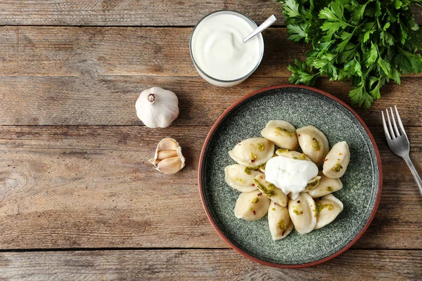 Heerlijke gekookte dumplings geserveerd op houten tafel, platte lag. Ruimte voor tekst — Stockfoto