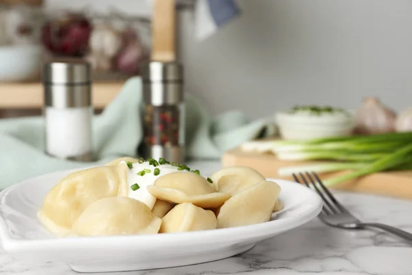 Heerlijke gekookte dumplings met zure room op witte marmeren tafel, close-up — Stockfoto