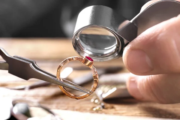 Male jeweler examining ruby ring in workshop, closeup view