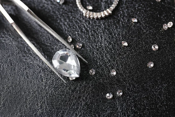 Siyah deri yüzeyde mücevherler ve cımbız — Stok fotoğraf
