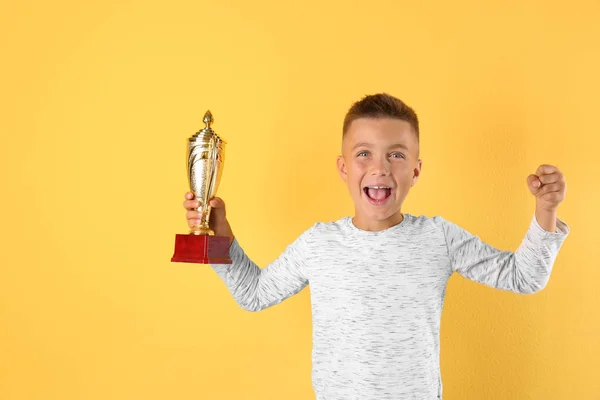 Felice ragazzo con coppa d'oro vincente su sfondo giallo — Foto Stock