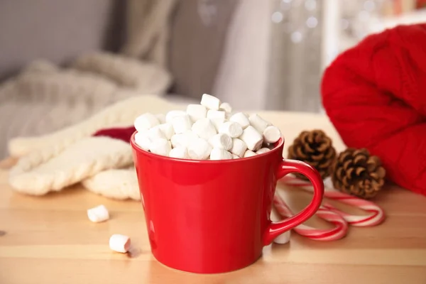 Cup of hot cocoa with marshmallows on wooden table indoors. Winter drink