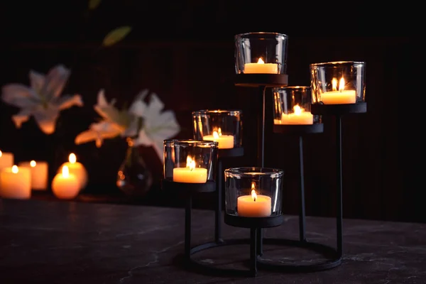 Suporte com velas acesas na mesa na escuridão, espaço para texto. Símbolo funerário — Fotografia de Stock