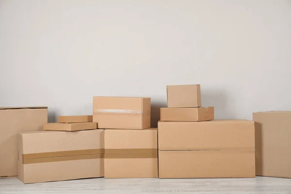 Pile of cardboard boxes near light wall indoors — Stock Photo, Image