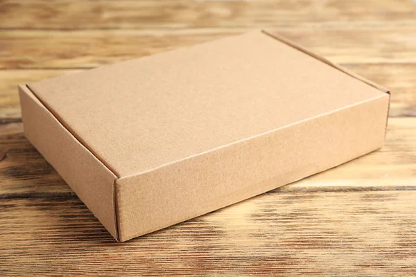 Kahverengi ahşap masa üzerinde kapalı karton kutu — Stok fotoğraf