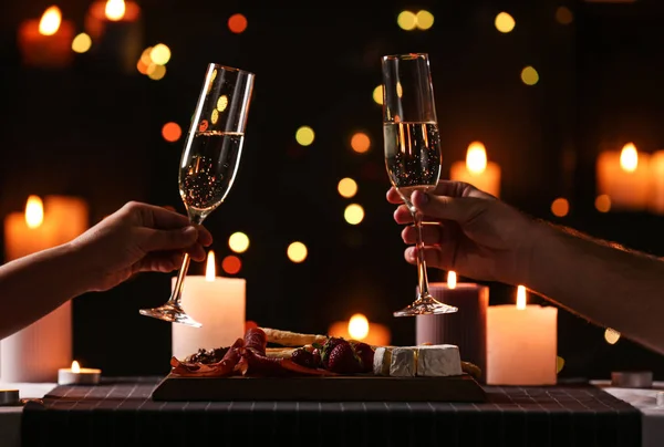 Junges Paar mit Champagnergläsern beim romantischen Abendessen bei Kerzenschein am Tisch, Nahaufnahme — Stockfoto
