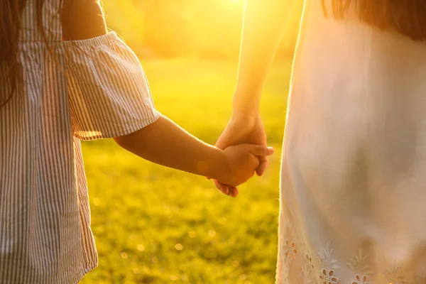 Маленькая девочка и ее мать держатся за руки в парке, крупным планом. Счастливая семья — стоковое фото