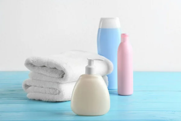 Produtos de higiene pessoal e toalhas dobradas em mesa de madeira azul claro — Fotografia de Stock