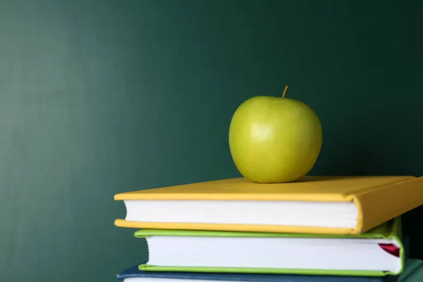 Books and apple near green chalkboard, space for text. School education Royalty Free Stock Photos