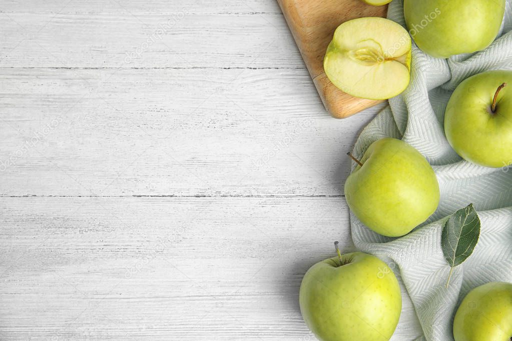 Flat lay composition of fresh ripe green apples on white wooden table, space for text