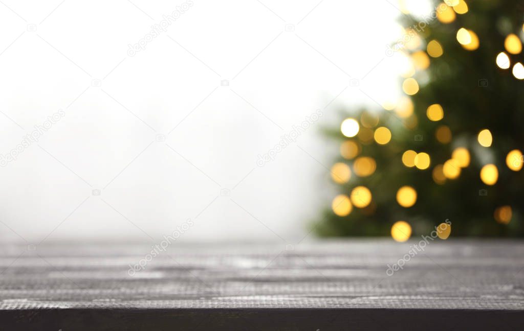 Empty table and blurred fir tree with yellow Christmas lights on background, bokeh effect. Space for design