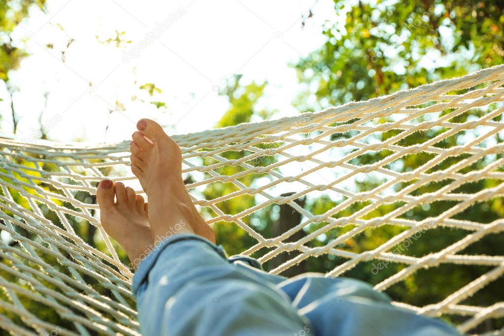 Young woman resting in comfortable hammock at green garden, closeup