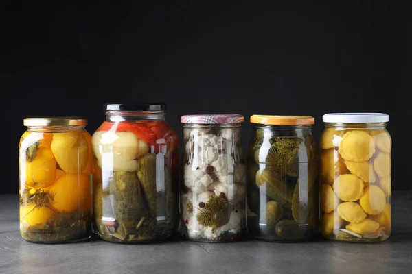 Jars of tasty pickled vegetables on grey table