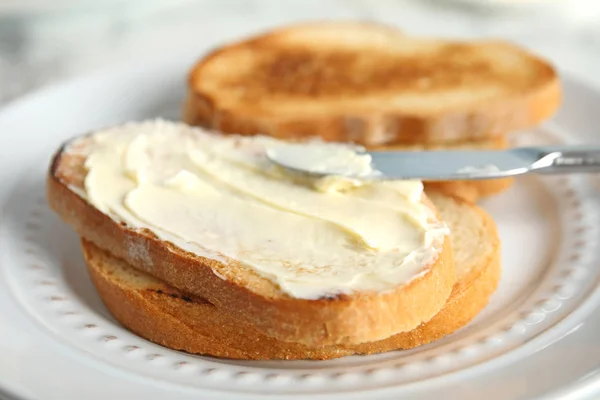 Pão saboroso com manteiga e faca no prato, close-up — Fotografia de Stock