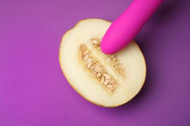 Mor arka plan üzerinde kavun ve vibratör yarısı, düz yatıyordu. Seks kavramı