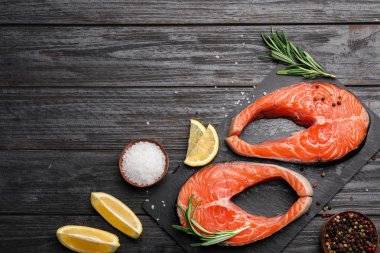 Siyah ahşap masa üzerinde taze somon biftek ile Düz yatıyordu kompozisyon, metin için alan