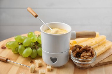 Ahşap masa üzerinde ekmek ile lezzetli peynir fondü ve çatal Pot