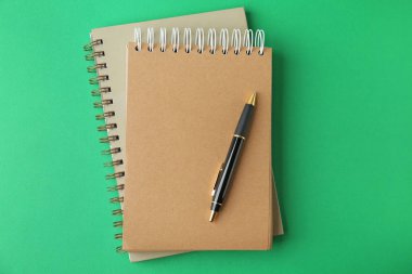 Yeşil arka plan daki dizüstü bilgisayarlar ve kalem, üst görünüm