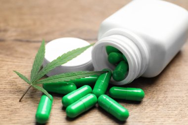 Kenevir yaprağı ve şişe ahşap masa üzerinde kapsül ile