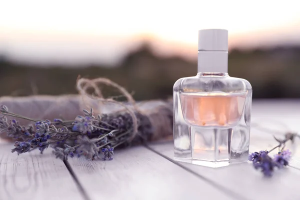 Sebotol parfum mewah dan bunga lavender di meja kayu putih di luar ruangan. Ruang untuk teks — Stok Foto