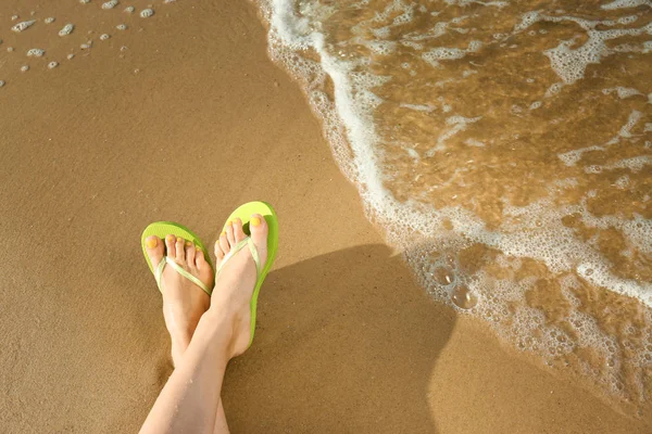 Nahaufnahme einer Frau mit Flip Flops auf Sand am Meer, Raum für Text. Strandzubehör — Stockfoto