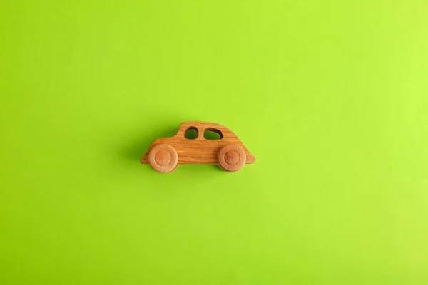 Wooden toy car on light green background, top view