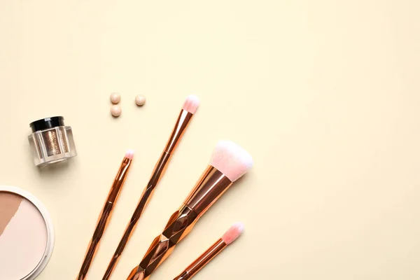 Flat lay composition with makeup brushes on beige background. Space for text