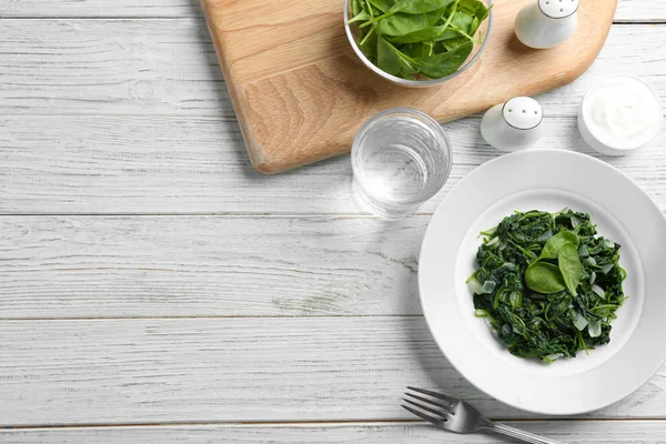 Platt Lay komposition med välsmakande kokt spenat och utrymme för text på vitt träbord. Hälsosam mat — Stockfoto